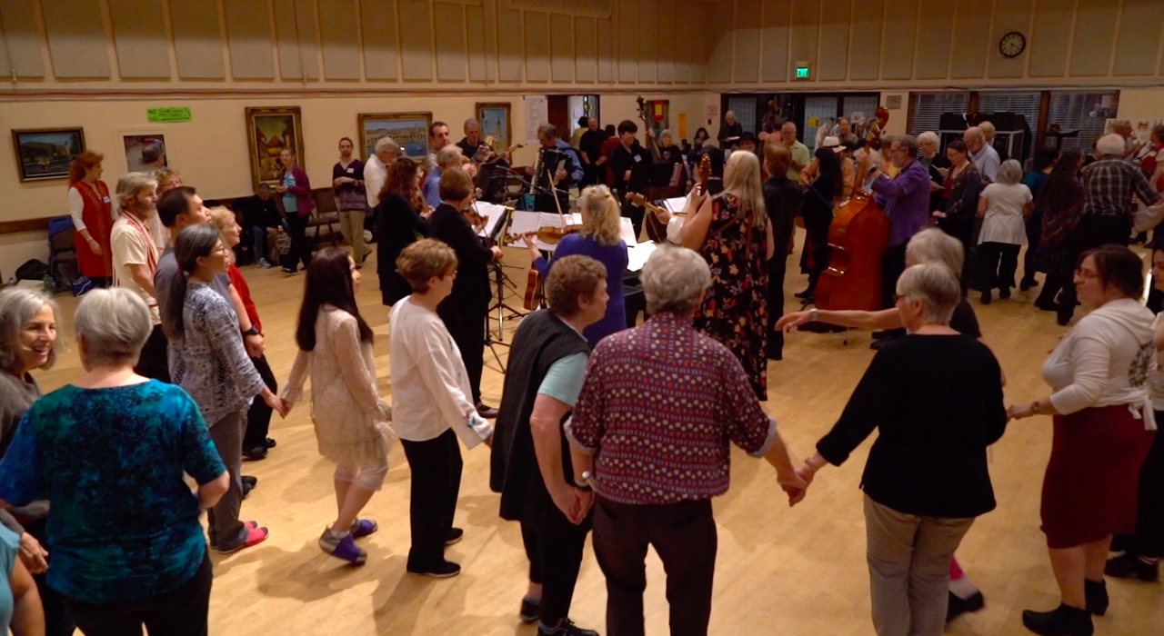 Wide view of the festival hall with musicians playing and dancers filling the floor