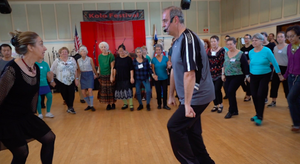 A dance instructor demonstrating steps as attendees follow along behind